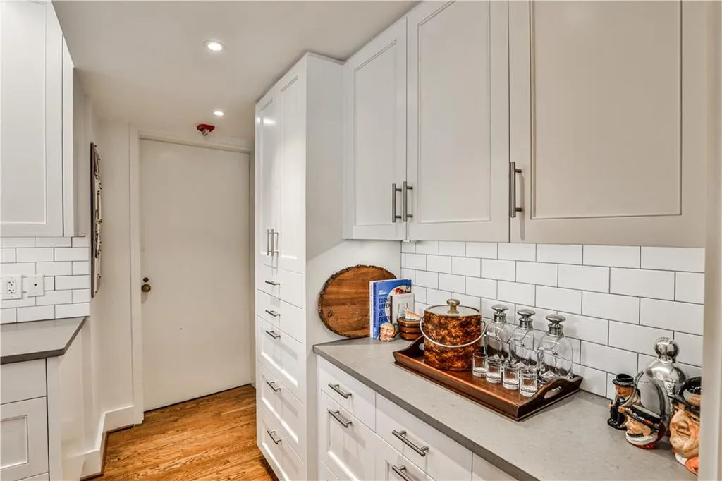Kitchen with light wood finished floors, white cabinets, tasteful backsplash, and recessed lighting