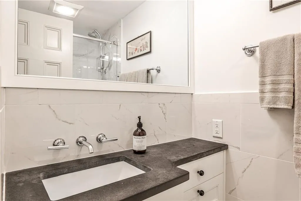 Bathroom featuring an enclosed shower, vanity, and tile walls