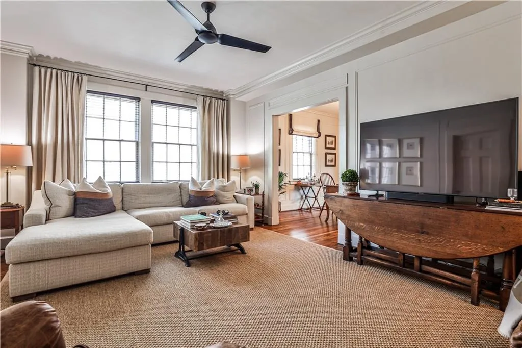 Living area featuring ceiling fan, crown molding, and carpet