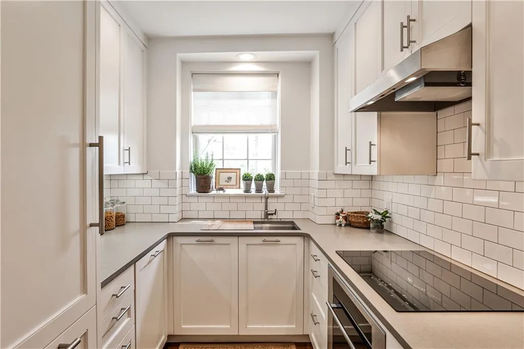 Kitchen featuring black electric stovetop, under cabinet range hood, wall oven, and white cabinets