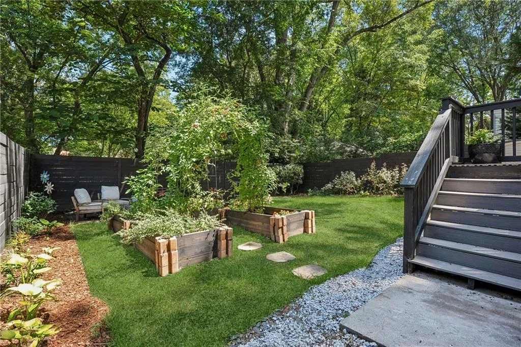 Fenced backyard featuring a vegetable garden and stairs