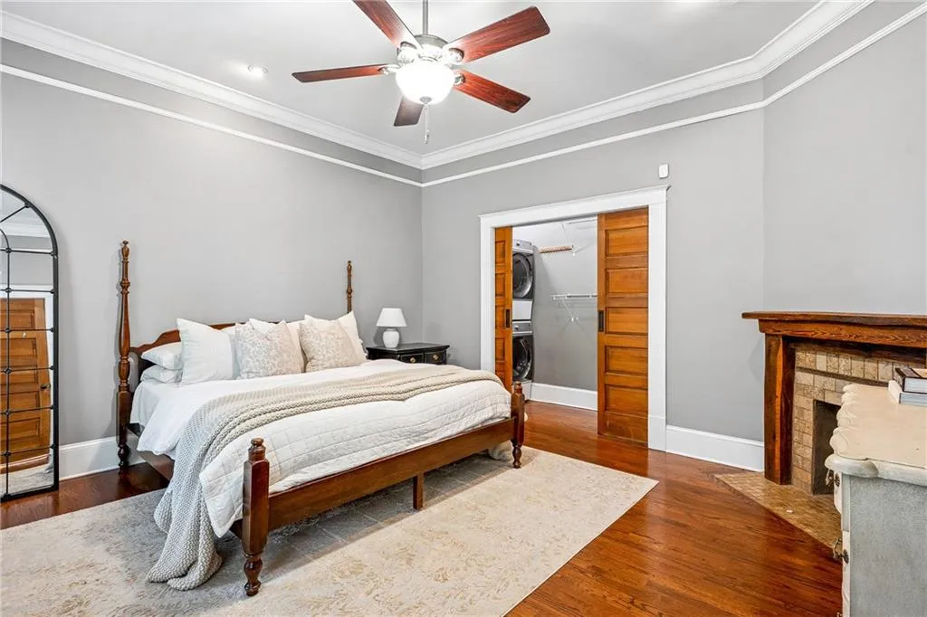 Bedroom featuring stacked washer / dryer, ornamental molding, wood finished floors, a spacious closet, and a ceiling fan
