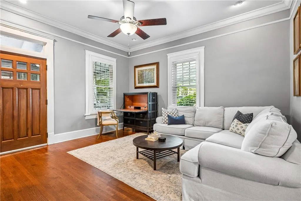 Living area featuring crown molding, wood finished floors, and ceiling fan