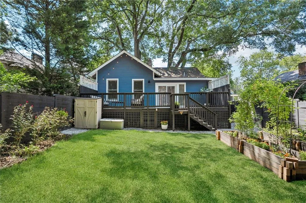 Rear view of property with a deck, a fenced backyard, a vegetable garden, and stairs