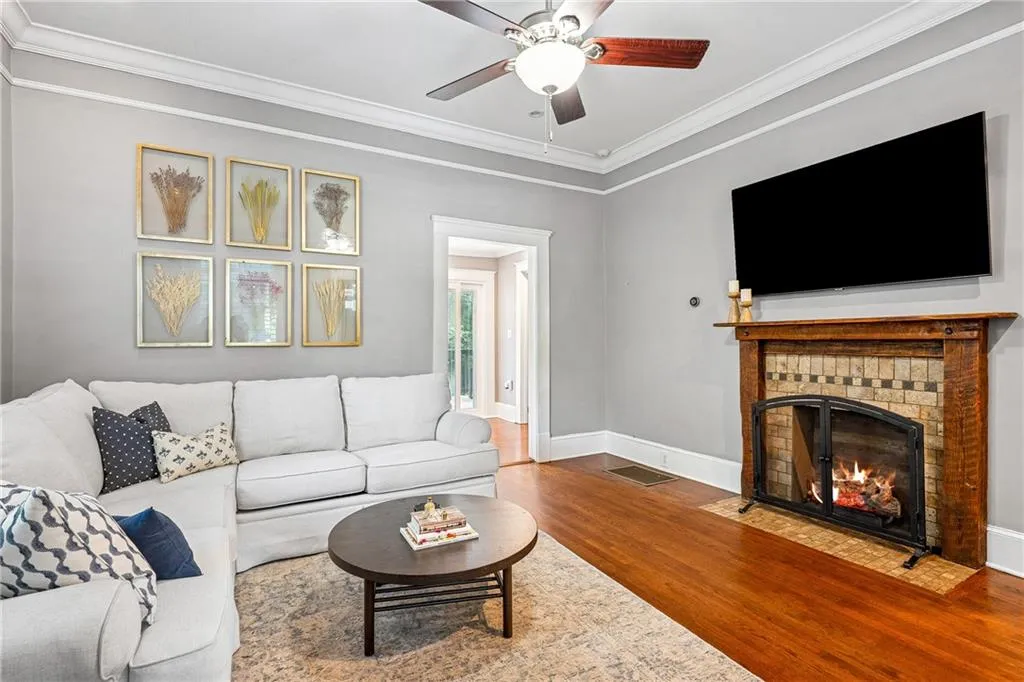 Living room with ornamental molding, a fireplace, wood finished floors, and a ceiling fan