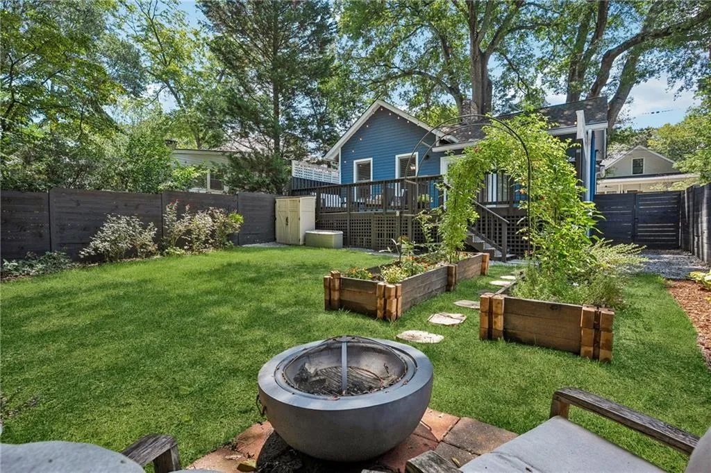 Fenced backyard featuring a wooden deck and a garden