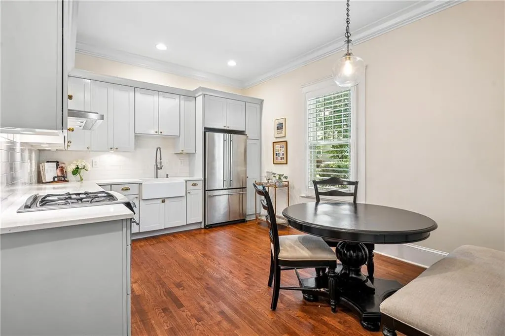 Kitchen with tasteful backsplash, light countertops, dark wood finished floors, freestanding refrigerator, and crown molding