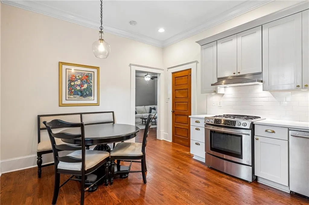 Kitchen featuring stainless steel appliances, crown molding, backsplash, light countertops, and dark wood-style flooring