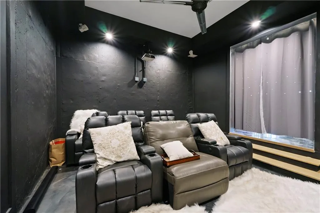 Media room featuring dark walls, ceiling-mounted projector, track lighting, and window with light-filtering curtains