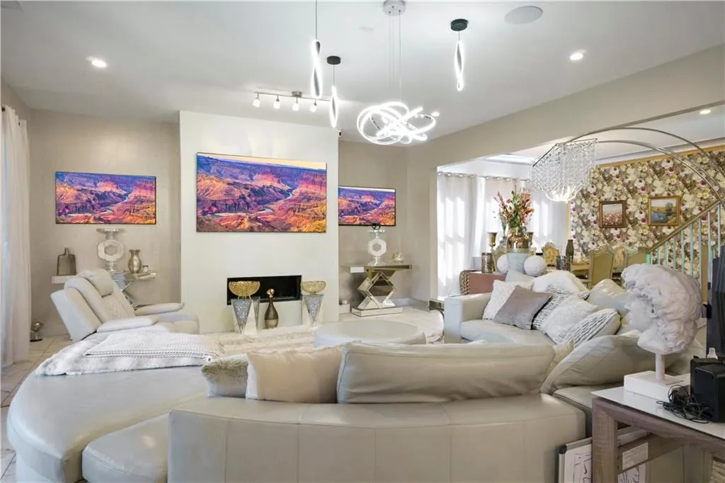 Recessed lighting, contemporary pendant lights, integrated fireplace, wall-mounted shelving, and a decorative staircase