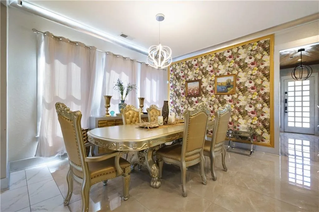 Recessed lighting, contemporary chandelier, large picture window with drapes, accent wall with framed floral wallpaper, and polished tile flooring