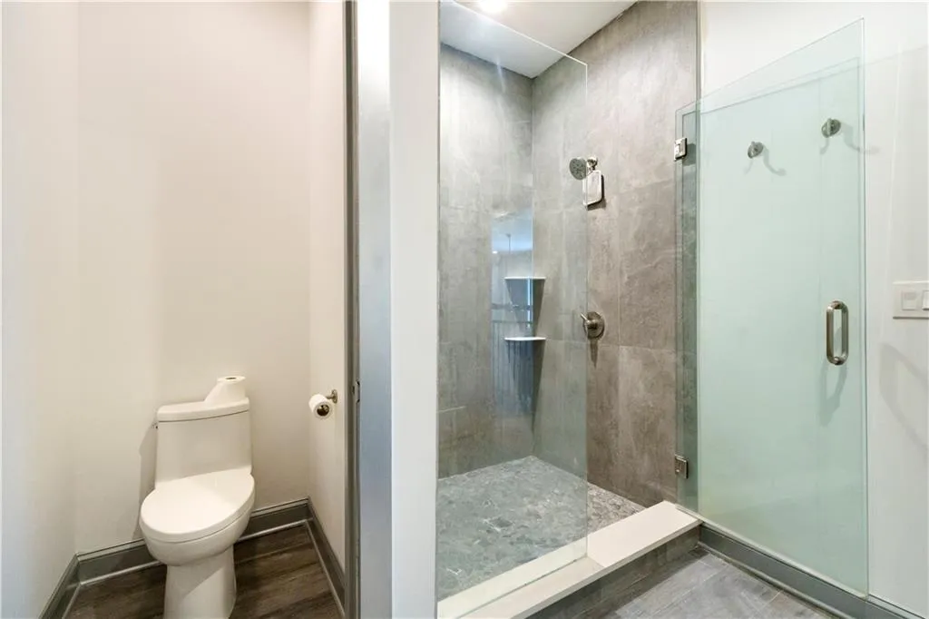 Walk-in shower with clear glass enclosure and stone-finish tile surround
