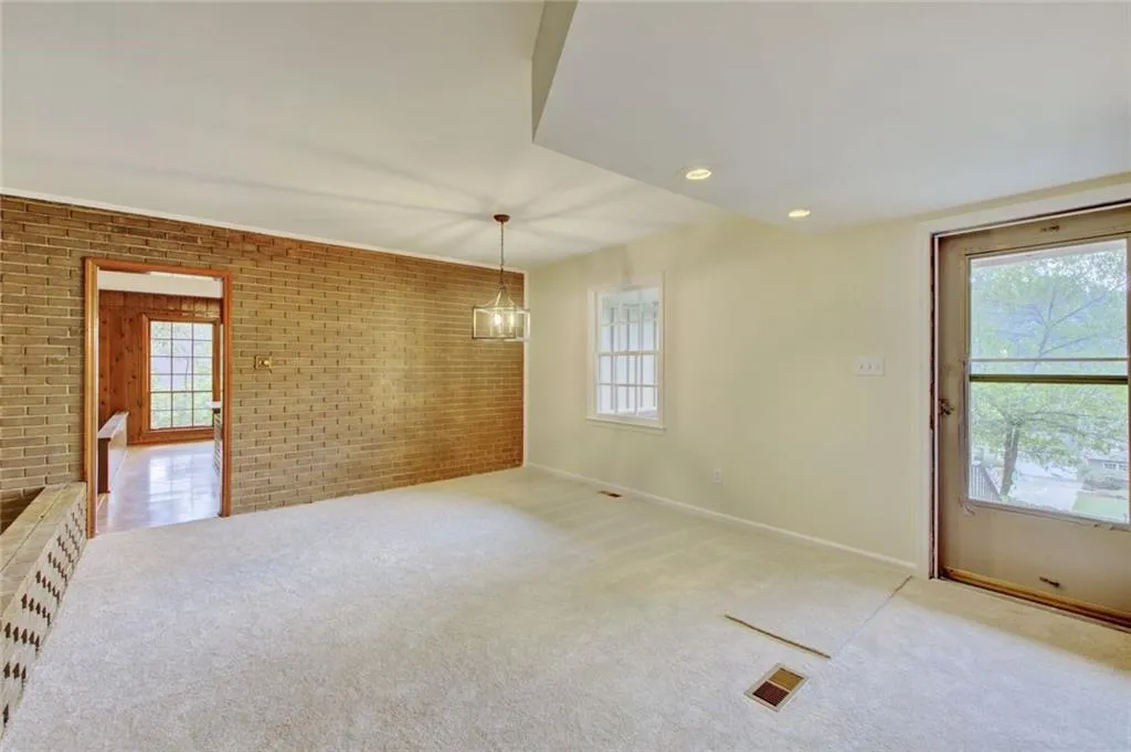 Unfurnished living room featuring brick wall, carpet, and a fireplace