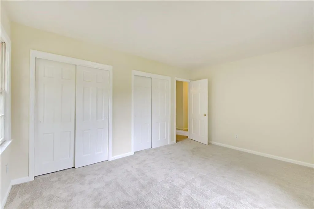 Unfurnished bedroom with multiple closets and light carpet