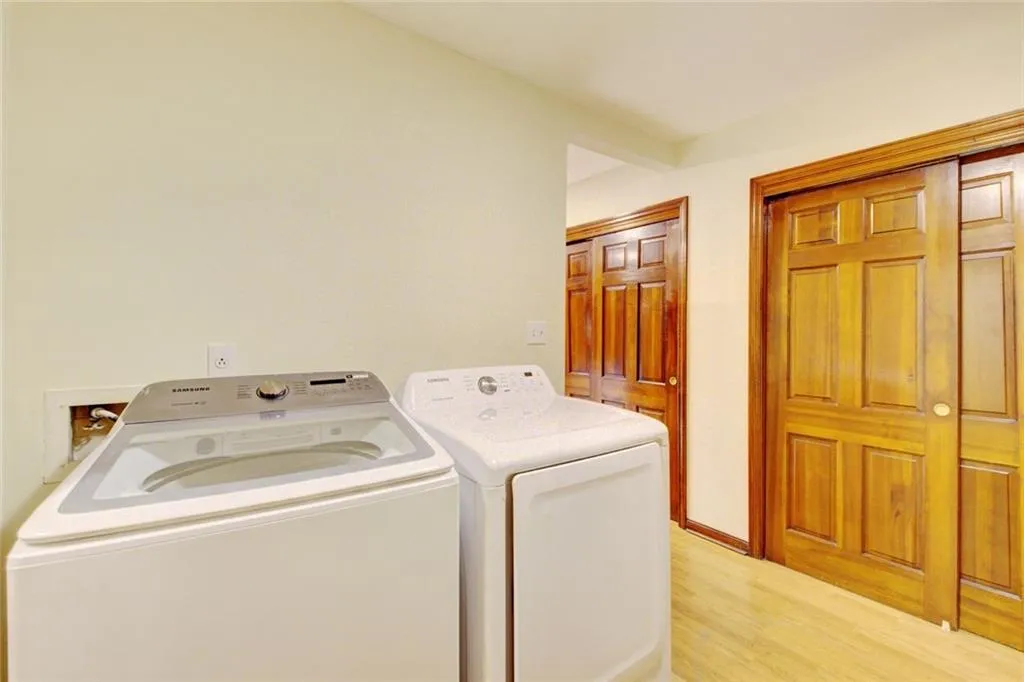 Laundry room featuring washing machine and clothes dryer and light hardwood / wood-style flooring