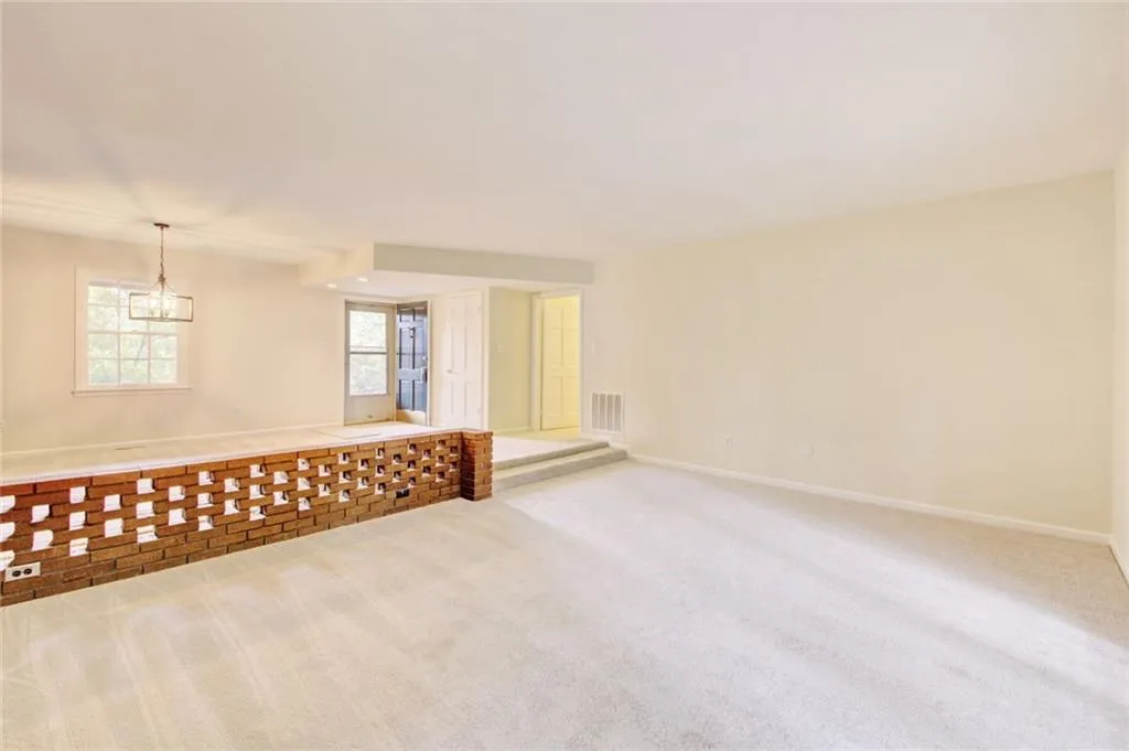 Unfurnished room with light carpet and an inviting chandelier
