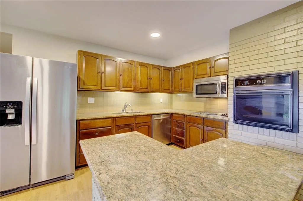 Kitchen with decorative backsplash, stainless steel appliances, sink, and light wood-type flooring