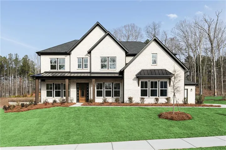 Traditional-style residence featuring a light-colored brick exterior with dark trim and a dark shingle roof