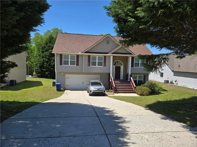 Split foyer home featuring a front yard, roof with shingles, a garage, and concrete driveway