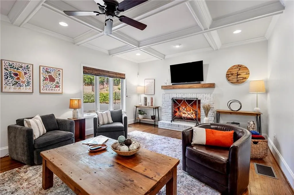 Living area with visible vents, baseboards, a brick fireplace, and wood finished floors