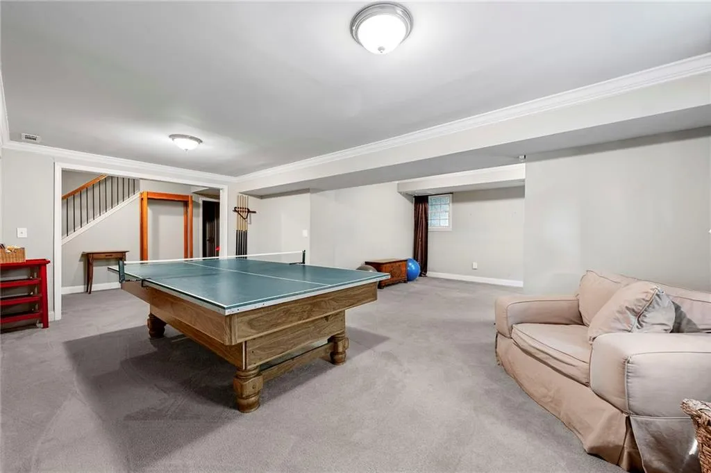 Recreation room featuring baseboards, light colored carpet, and ornamental molding