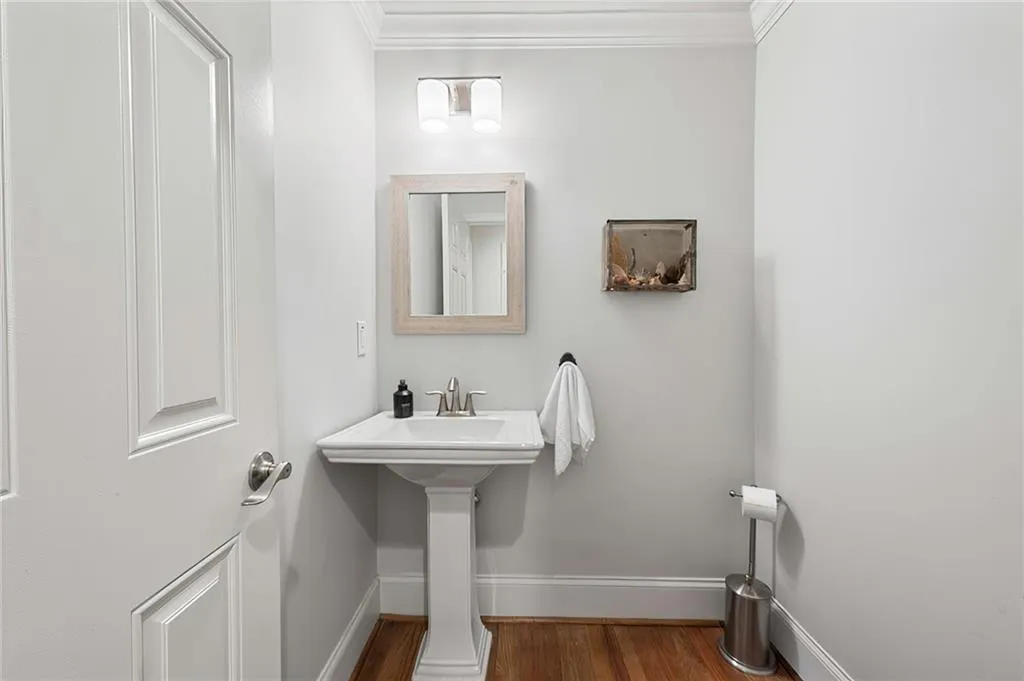 Powder Bathroom featuring wood finished floors, baseboards, and ornamental molding
