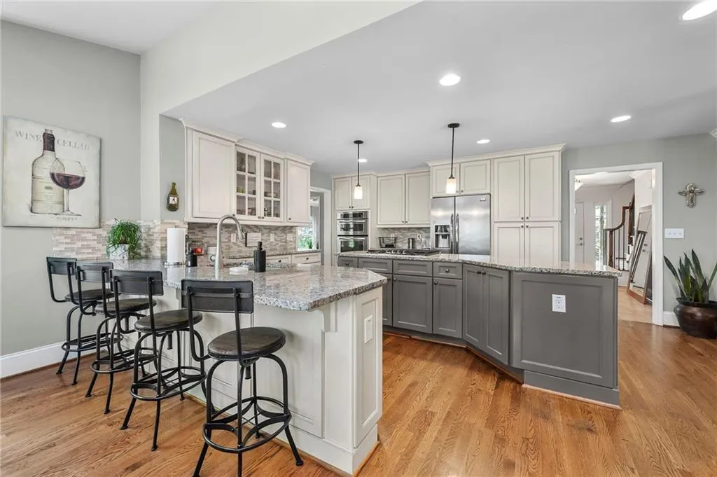 Kitchen with a peninsula, glass insert cabinets, gray cabinetry, appliances with stainless steel finishes, and a sink