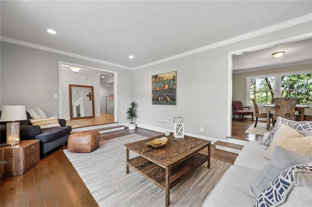 Living room with visible vents, baseboards, ornamental molding, recessed lighting, and wood finished floors