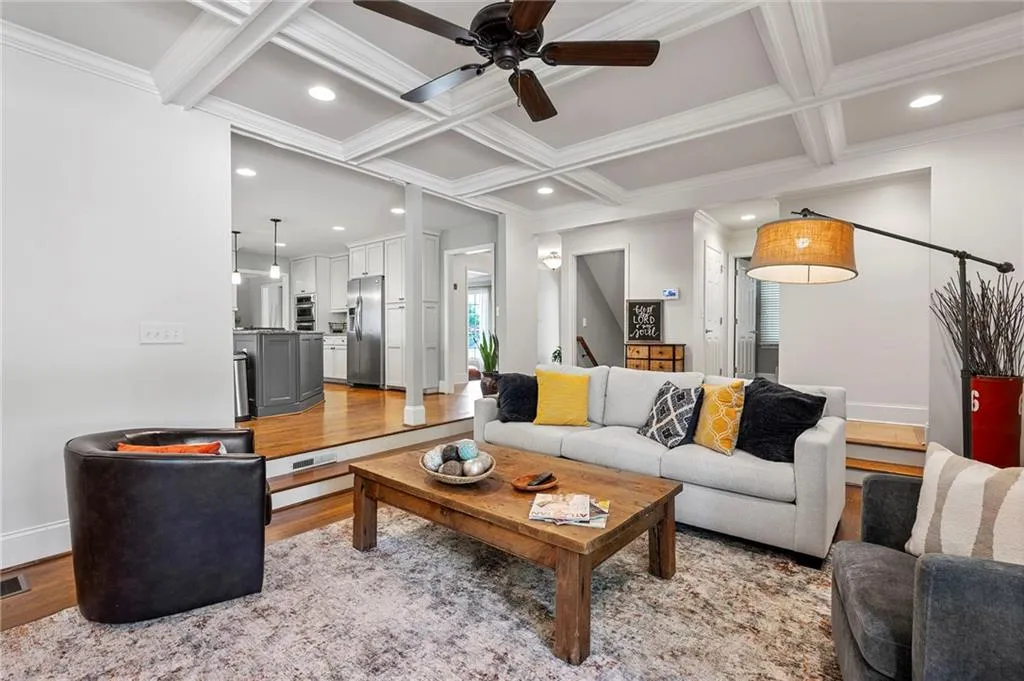Living area featuring ornamental molding, light wood-style flooring, ceiling fan, and coffered ceiling