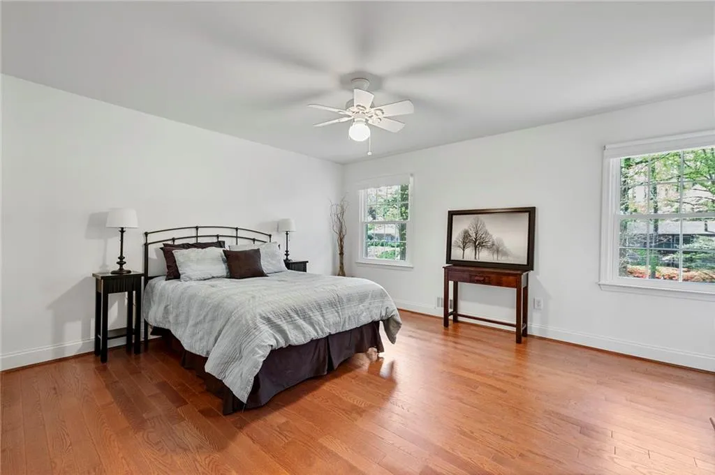 Bedroom featuring a ceiling fan, wood finished floors, baseboards, and multiple windows