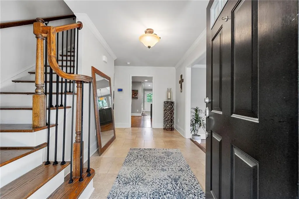 Foyer entrance featuring light tile patterned floors, baseboards, ornamental molding, and stairs
