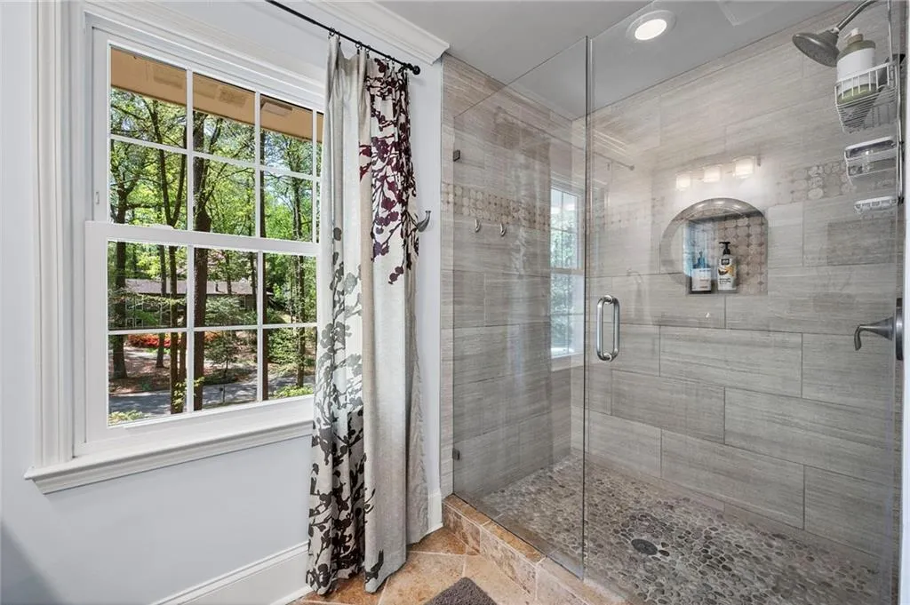 Full bathroom featuring baseboards, a stall shower, and a healthy amount of sunlight