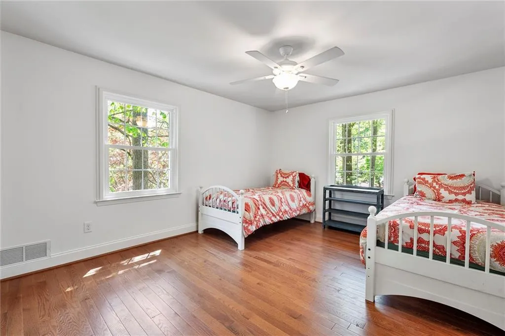 Bedroom featuring visible vents, baseboards, a ceiling fan, and wood-type flooring