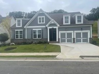 Siding and stone exterior with white trim details, dormer windows, and a two-car garage