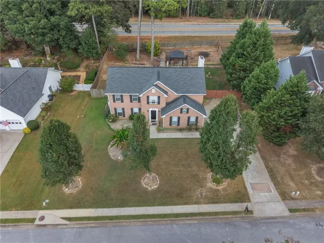 Two-story brick exterior with dark shutters, covered front entry, attached garage, and a concrete driveway