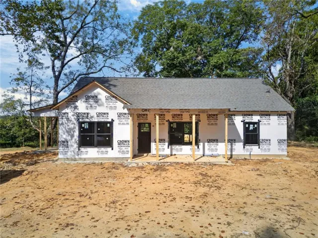 New construction featuring a composition shingle roof, black window frames, and a prominent front door