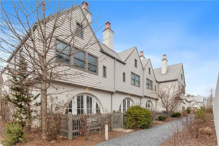 Multi-level residence featuring a gray metal roof, light-colored horizontal siding, and multiple chimneys