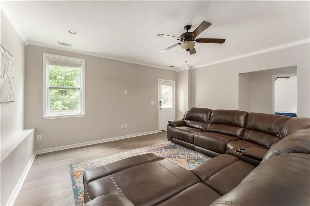 Living area with ornamental molding, wood finished floors, and a ceiling fan