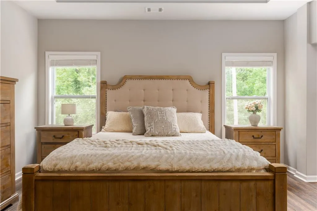 Bedroom featuring dark wood-type flooring and multiple windows