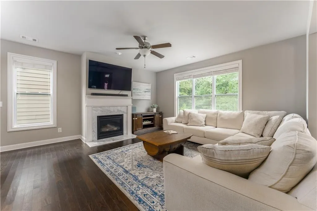 Living area featuring a high end fireplace, dark wood finished floors, and ceiling fan