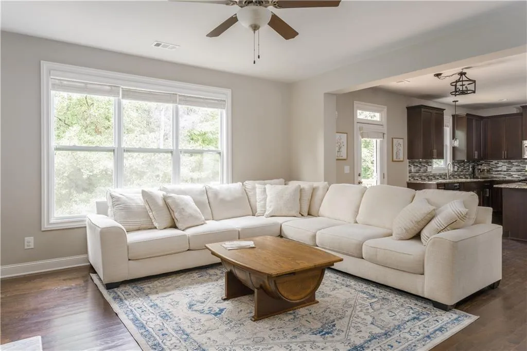 Living room featuring ceiling fan and dark wood-style flooring