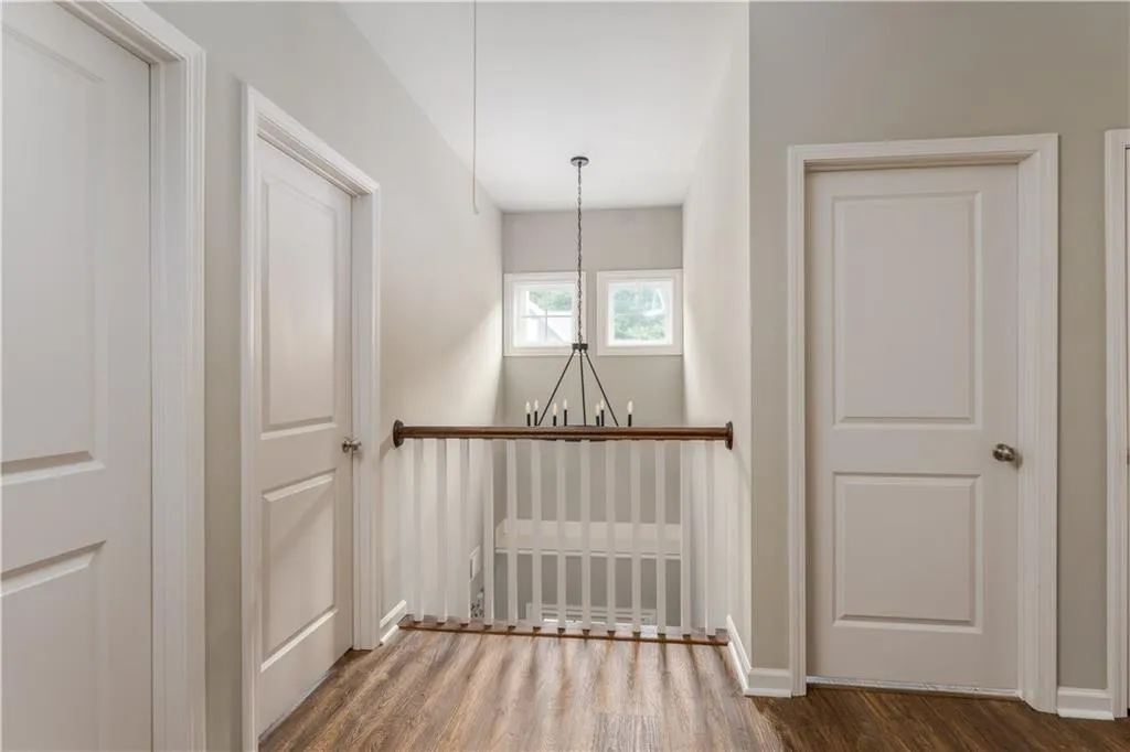 Corridor with dark wood-style flooring and a chandelier