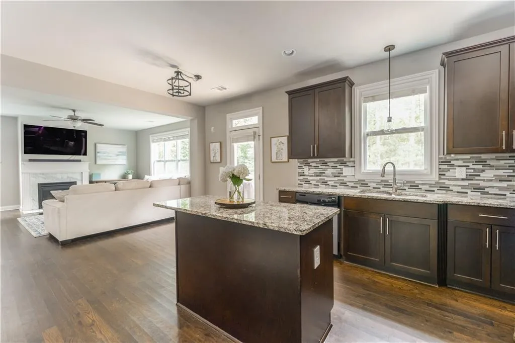 Kitchen with dark brown cabinetry, dark wood-style flooring, a ceiling fan, a center island, and backsplash