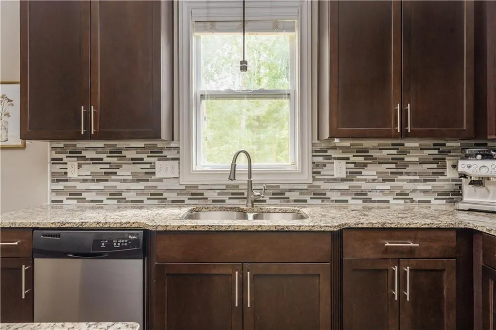 Kitchen featuring dark brown cabinets, dishwasher, tasteful backsplash, and light stone countertops