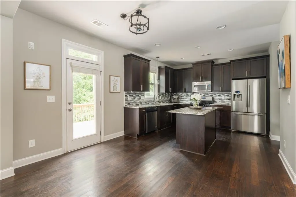 Kitchen featuring stainless steel appliances, dark brown cabinetry, tasteful backsplash, dark wood-type flooring, and a kitchen island