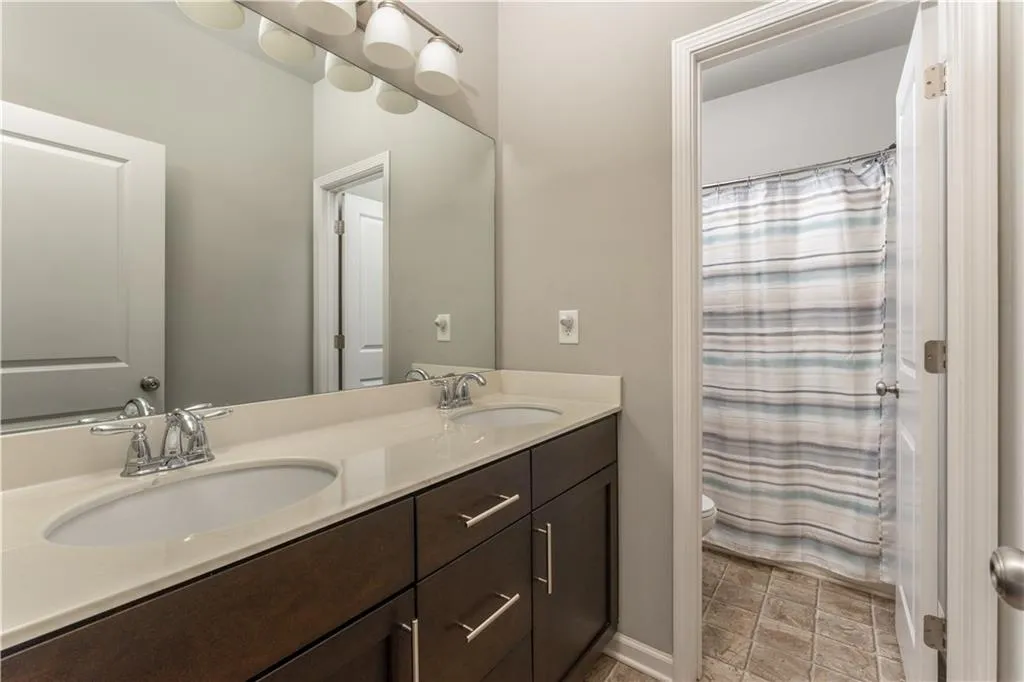 Full bathroom featuring double vanity and curtained shower