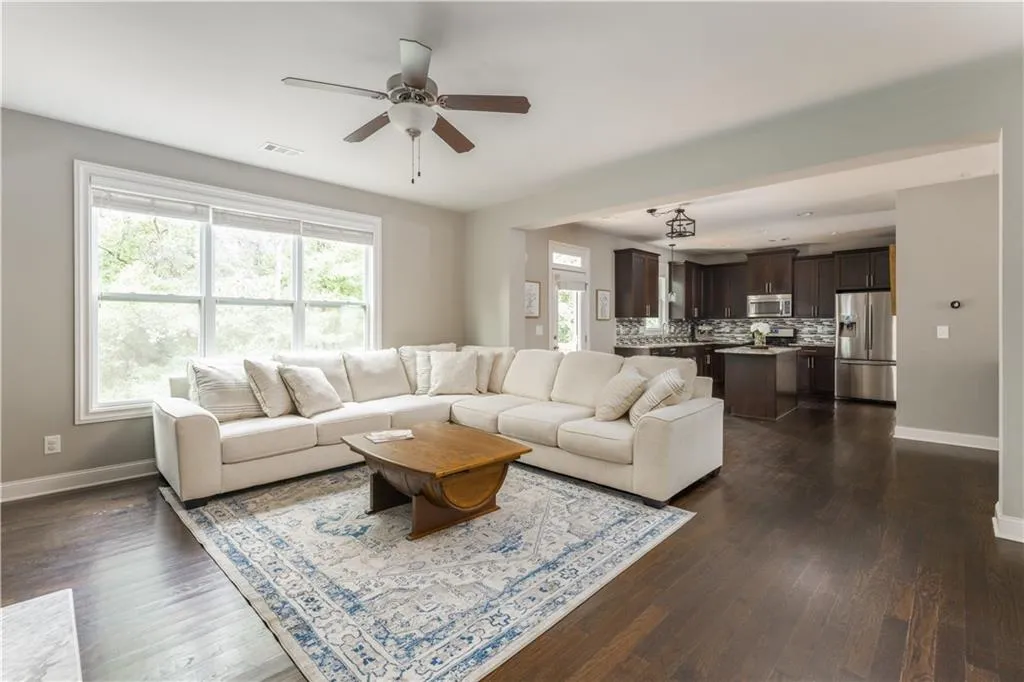 Living room with a ceiling fan, healthy amount of natural light, and dark wood-type flooring
