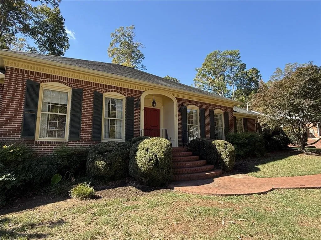 View of front facade with brick siding, a porch, and a front lawn