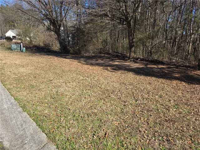 Cleared lot featuring a concrete border and a wooded perimeter
