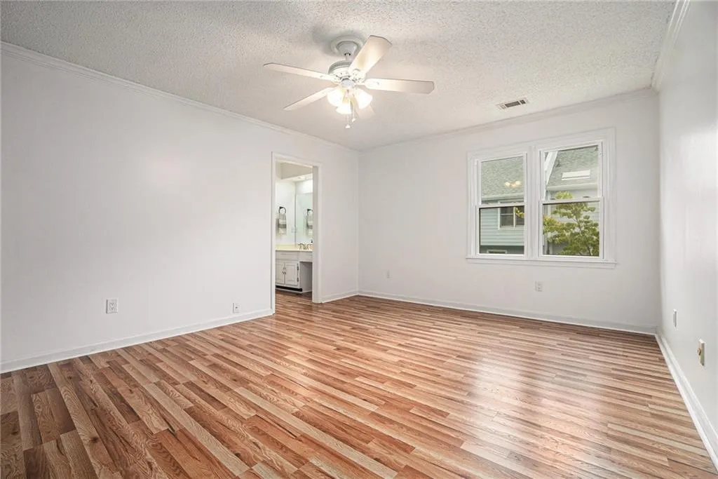 Unfurnished room with light wood-style floors, a textured ceiling, ornamental molding, and a ceiling fan Unfurnished room with light wood-style floors, a textured ceiling, ornamental molding, and a ceiling fan